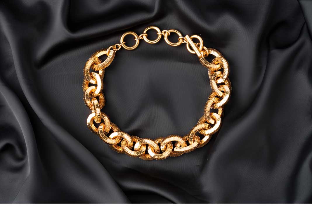 gold-chain-on-black-silk-fabric-background-ngcm